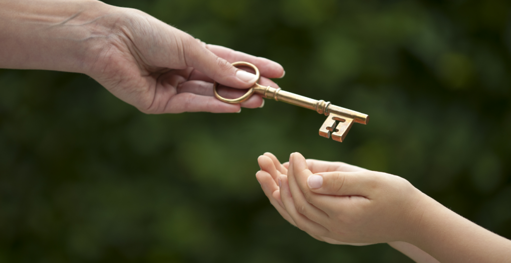 older woman handing over and old key to a child