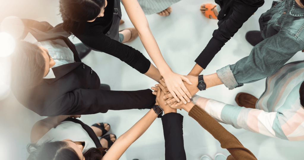 group of people putting hands in a circle