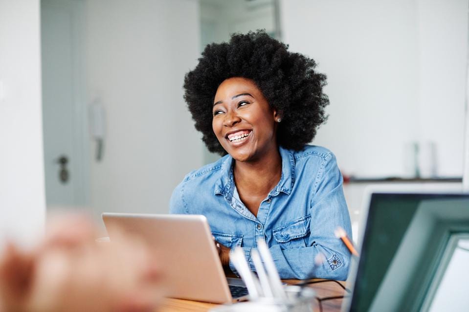 woman smiling in front of laptop at a desk