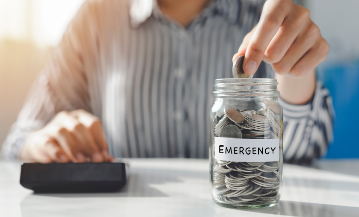 woman putting coins in an emergency fund jar