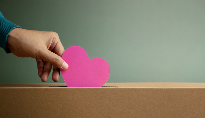 hand dropping a paper heart into a box