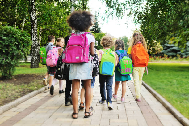 kids walking with backpacks down sidewalk