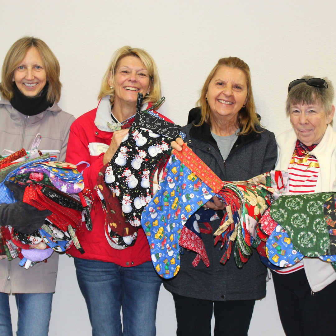 volunteers hold up christmas stockings