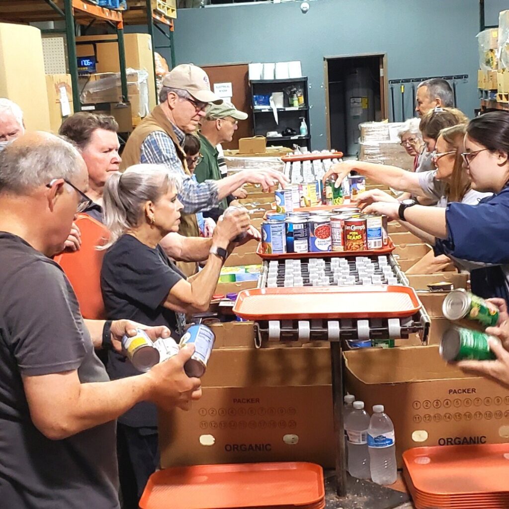 food pantry volunteers load boxes and trays with canned foods