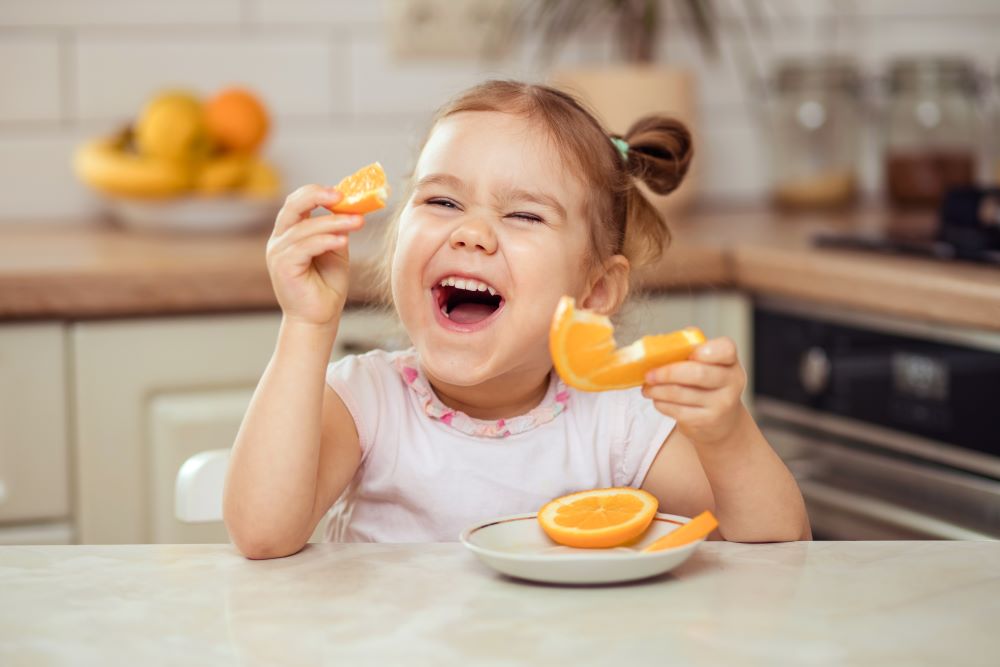 Little girl eating an orange